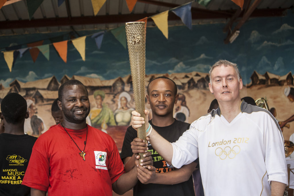 Father John, Abdi Rauf, and John pose with the torch