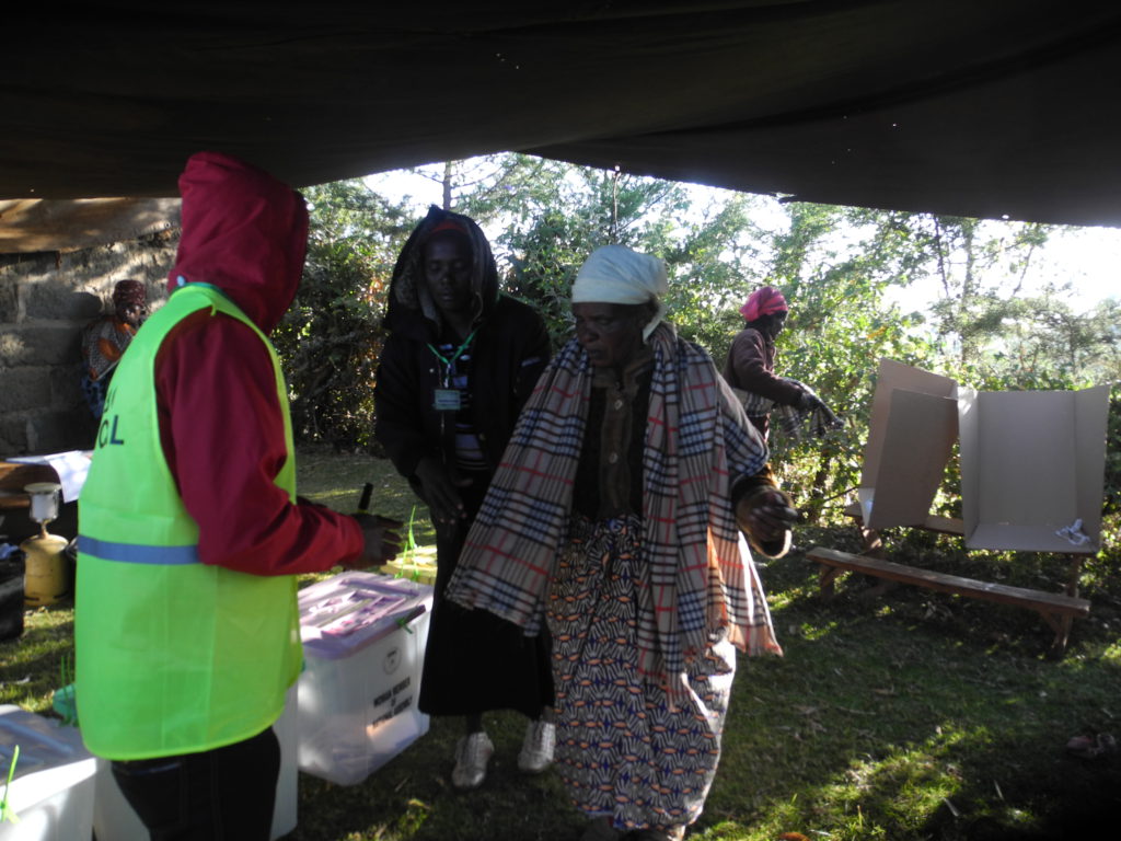 Mrs Lucia Nyamunyu Kabiru, a mother of 10, aged 70, ( right) is assisted by polling officials to cast her ballot at Kadenye polling centre, in Molo, in the Rift Valley.