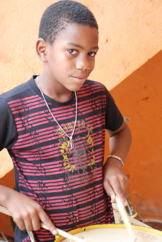 Young boy taking part in a drumming workshop with GSASC in Olinda