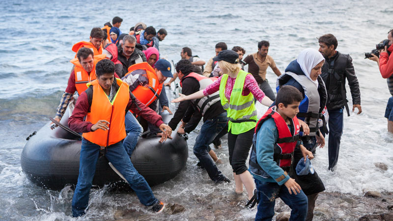 Volunteers help refugees to shore in Lesbos
