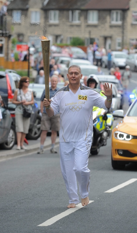 John runs barefoot with the Olympic torch. Photo credit: Craig Connor North News & Pictures Ltd