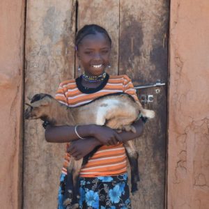 African girl holding the goat she received from CAFOD