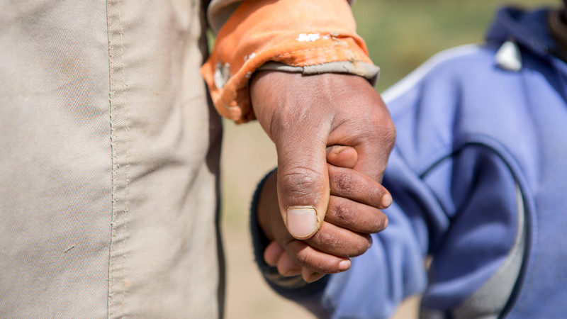 Vladimir, from Bolivia, holds hands with his son Alex