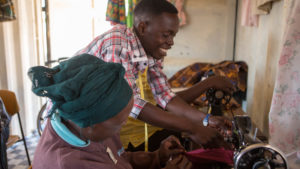 Patrick is teaching tailoring in a school powered by Solar Panels. The school aims to support people in the district who are living with disabilities.