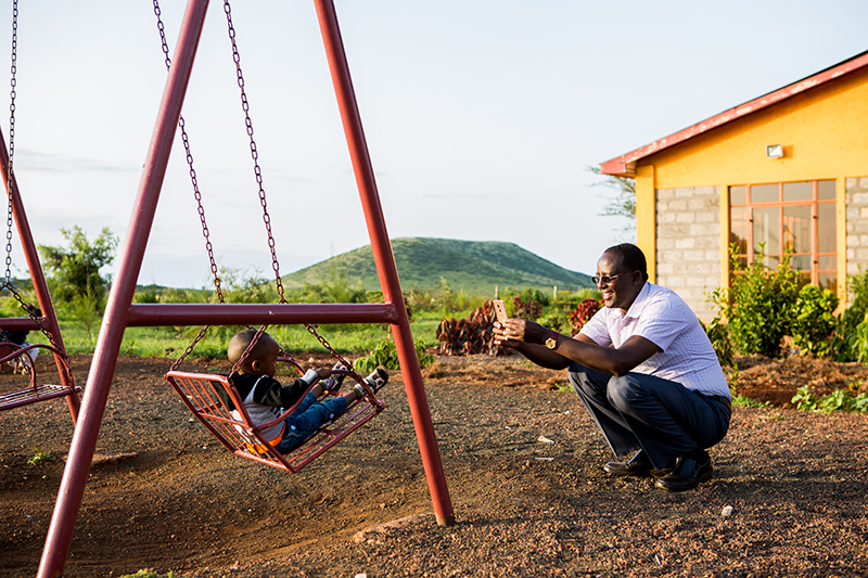 Isacko Jirma with his son on a swing, in Kenya.