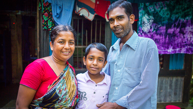 Eshita stands smiling with her son and husband