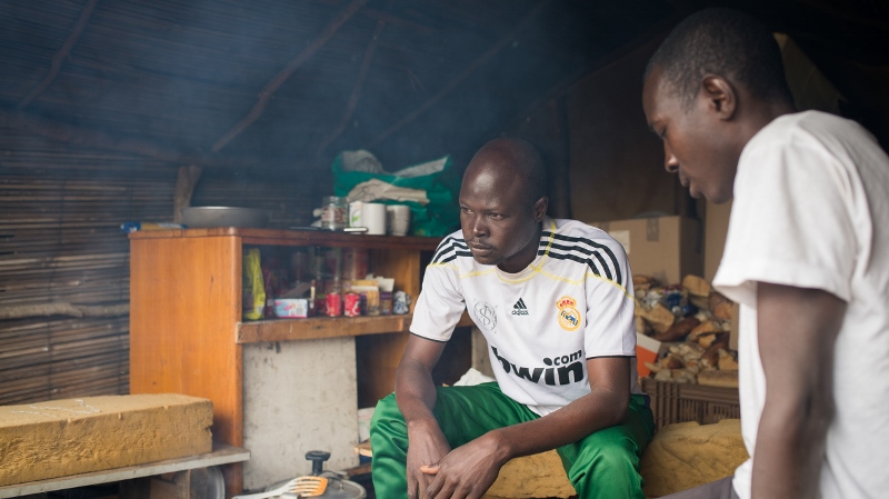 Two men sitting in a shelter in a refugee camp outside of Calais