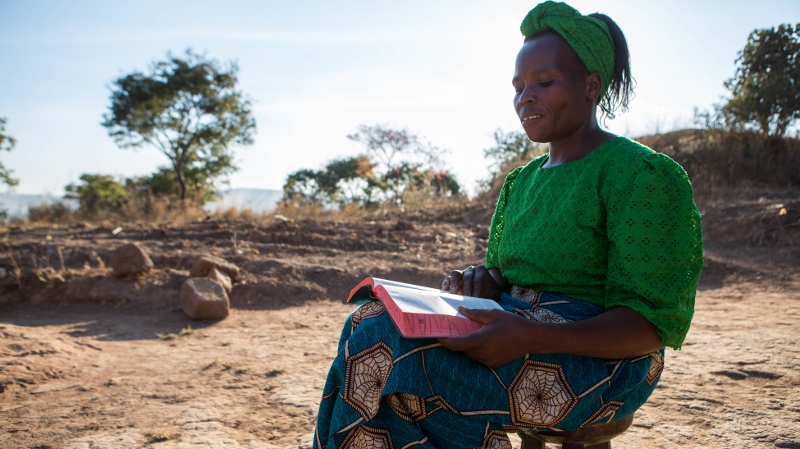 Beauty sits outside her home in Zambia reflecting on the Bible