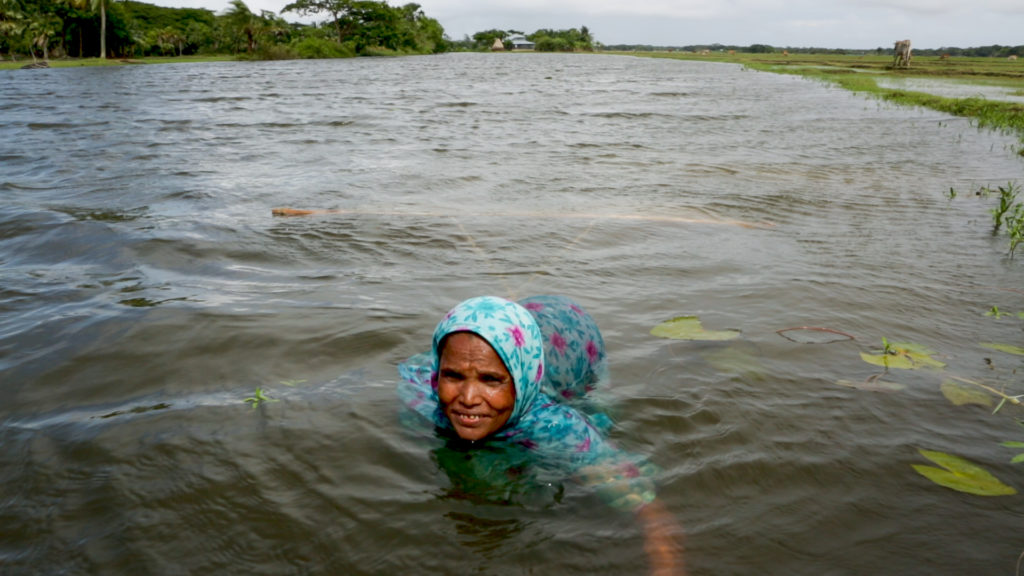 Mahinur fishing in the river. She works hard to try and provide for her family.