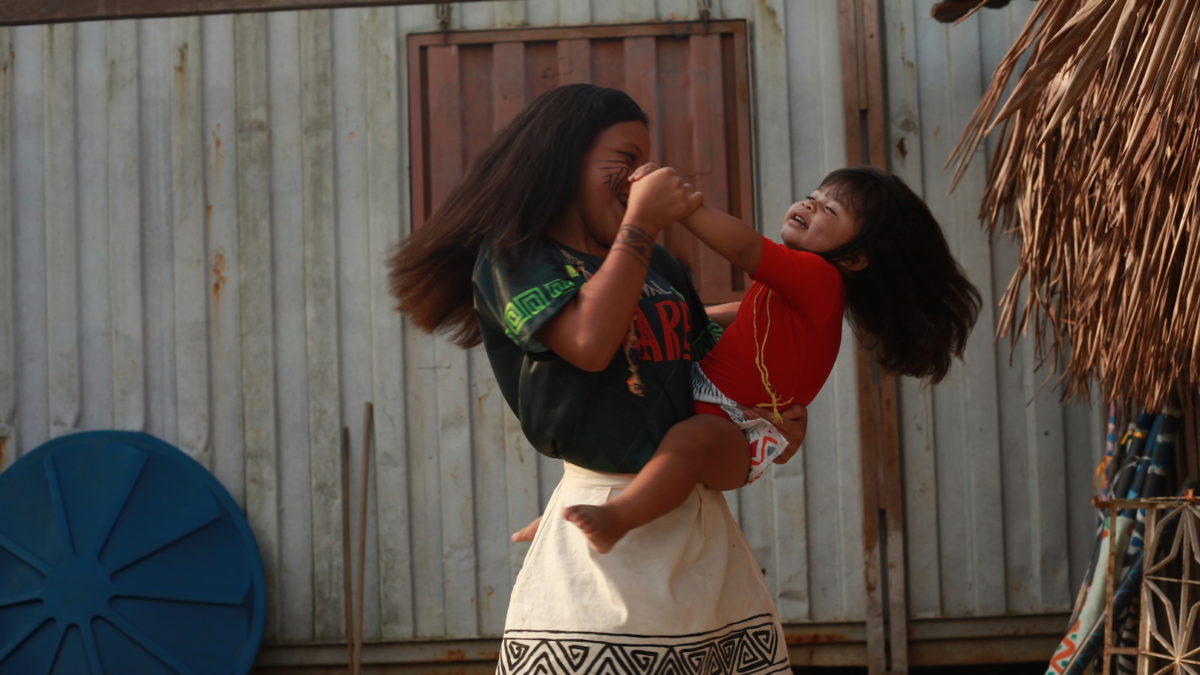 At a festival celebrating indigenous culture, Manaus, Brazil a girl dances with a young child