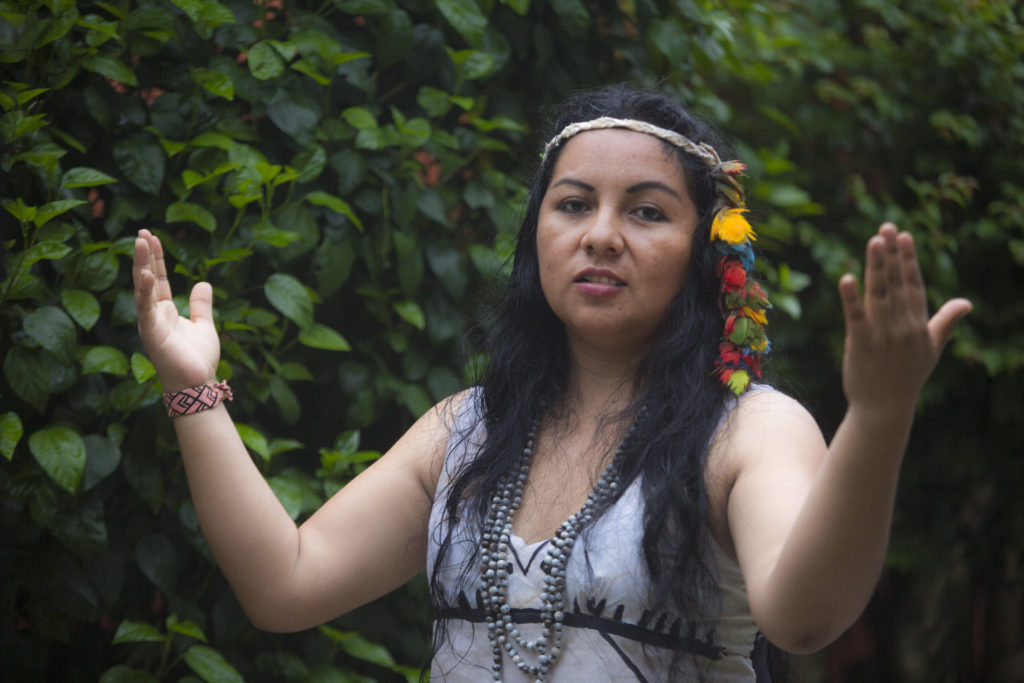 Yesica, an indigenous woman from the Peruvian Amazon stands with arms outstretched in prayer