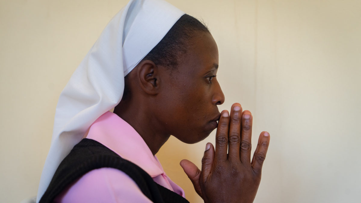 Sister Consilia stands with her hands clasped in prayer