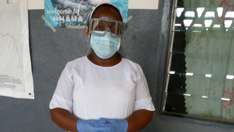 Sister Gertrude standing in her clinic wearing goggles, face mask and gloves