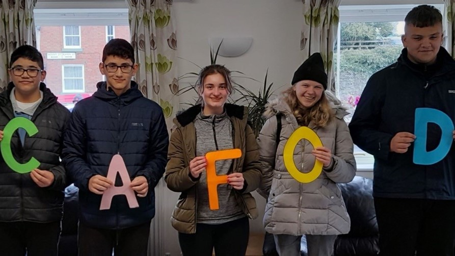 Five people stand in a line, each holding brightly coloured letter to spell out CAFOD
