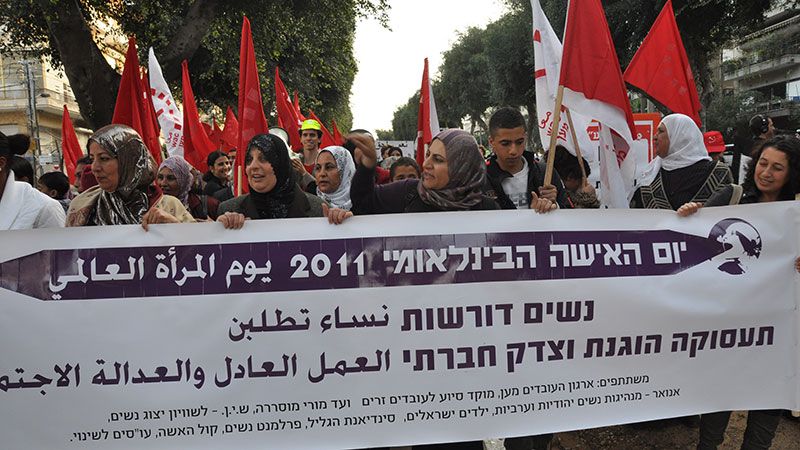 Marchers holding a wide banner and carrying flags